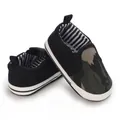 Gedetailleerd overzicht van babyloopschoenen met zachte zool, camouflage en zwart canvas. - Zwart