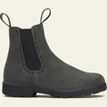 Vista detallada de botines Chelsea de ante gris con perforaciones decorativas estilo brogue. - Gris
