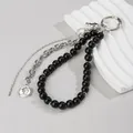 Gros plan d'un porte-clés en perles noires avec chaînes argentées sur support blanc - Style à Perles Croix et Pièce (ZJ15967)