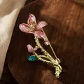 Detail view of an elegant enamel flower brooch with rhinestones and green crystal leaf - Pink
