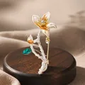 Detailed macro view of an elegant enamel flower brooch featuring a sparkling crystal center - White