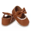Detail view of brown faux leather baby walking shoes with bow and white scalloped trim. - Brown