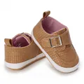 Nahaufnahme brauner Baby-Lauflernschuhe mit weicher weißer Sohle und Schnallenriemen - Aprikose
