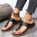 Close-up of black wedge thong sandals featuring decorative stitching and metal buckle - Black