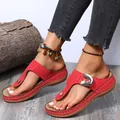 Detailed view of women's red wedge flip-flop sandals featuring decorative metal buckles - Red