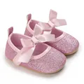 Close-up of pink glitter baby princess shoes featuring satin bows and soft rubber soles - Pink