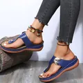 Lifestyle shot of blue wedge thong sandals with metal buckle and white stitching details - Blue
