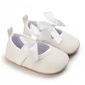 Close-up detail of white glittery baby girl princess shoes with a large satin ribbon bow - White
