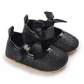 Close-up of elegant black glitter baby girl princess shoes with large satin bows - Black