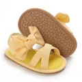Close-up of yellow baby girl sandals with large bows and non-slip soft rubber soles - Yellow