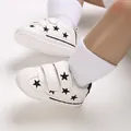 Close-up of white baby sneakers with black star embroidery and Velcro straps - White Black Star
