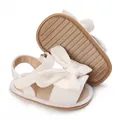 Detail view of baby girl sandals featuring a large bow and anti-slip rubber soles - White
