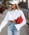Detailed view of a stylish white cropped long-sleeve shirt with a modern raw hem edge - White
