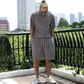 Detail view of a men's loose-fit grey vertical pleated short sleeve and shorts set outdoors - Gray