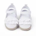 Vista detallada de los zapatos blancos para bebé con bonitos volantes y suela trenzada. - Blanco