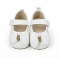 Détail de chaussures de marche pour bébé fille avec nœud blanc et centre doré scintillant. - Blanc