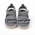 Primer plano de zapatos grises para bebé con volantes y suela de esparto trenzada - Gris