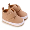 Close-up of tan canvas baby walking shoes with soft white soles and velcro straps. - Brown
