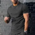 Primo piano di una t-shirt grigio antracite da uomo con girocollo in contesto urbano - Grigio scuro