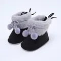 Nahaufnahme von Baby-Winterschuhen mit Pelzbesatz und lavendelfarbenen Bommeln - Schwarz