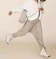 Action shot of woman wearing loose khaki overalls with pockets and fleece jacket - S / Jumpsuits / Gray