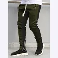 Detailed view of olive green joggers with black side stripes and ankle zippers. - M / Bottoms / Green & Black