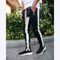 Detail view of men's track pants featuring white side stripes and ankle zipper - Black & White