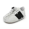 Vista lateral de zapato blanco para bebé con diseño M negro y cordones ajustables - Azul