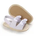 Close-up of white infant sandals showing cotton fabric bows and non-slip soft soles - White