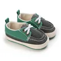 Nahaufnahme von grün-grauen Baby-Stoffschuhen mit weichen Sohlen für Lauflerner - Grün