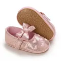 Detailed close-up view of pink glittery baby girl shoes with heart embroidery and bow - Pink