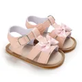 Detailed view of pink baby girl sandals with patent leather bow and buckle strap - Pink