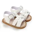 Detailed close-up of white baby girl sandals with bow tie and anti-slip rubber sole - White
