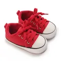 Vue rapprochée de baskets rouges pour bébés avec semelles souples et bouts classiques. - Rouge