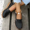 Detailopname van zwarte loafers met zachte zool en witte stiksels op houten ondergrond - 35 / Zwart