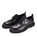Professional detail shot of black leather brogue shoes with classic wingtip carving details. - Black