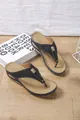 Side view of black wedge flip-flops with intricate cutouts and a decorative gold buckle. - 36 / Black