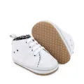 Close-up van witte baby canvas schoenen met antislip rubberen zolen met stippen. - Wit