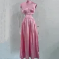Detail view of the pink satin waist-baring maxi dress on a clear mannequin - Pink