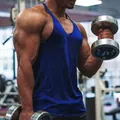 Close-up detail of a men's royal blue cotton fitness y-back tank top in a gym setting - Blue
