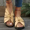 Stijlvolle beige sandalen met sleehak en strik gedragen op een terras van houten vloer - Geel