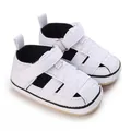 Close-up view of white canvas baby sneakers with soft non-slip rubber soles for infants. - White
