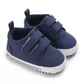 Macro view of dark blue canvas baby sneakers with double Velcro straps - Blue