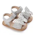 Close-up detail of silver glitter baby sandals featuring intricate butterfly wing decorations - Silver