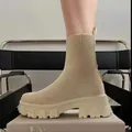 Close-up of women's beige knit sock boots featuring a chunky platform lug sole design. - Beige