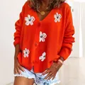 Dettaglio del cardigan in maglia arancione con delicati motivi floreali ricamati bianchi - Rosso