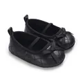 Detail view of black quilted baby girl flat shoes featuring a cute bow and elastic strap - Black