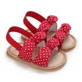 Primer plano de sandalias rojas de lunares para bebé con lazos y suela blanda - Rojo