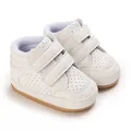 Close-up of white leather baby walking shoes with velcro straps and breathable holes - White