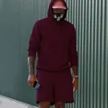 Modelo con un conjunto de sudadera con capucha y pantalones cortos de forro polar granate - Burdeos
